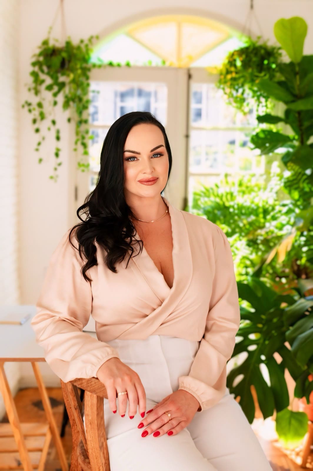Dra. Fernanda Wolff sentada em um ambiente claro, cheio de plantas